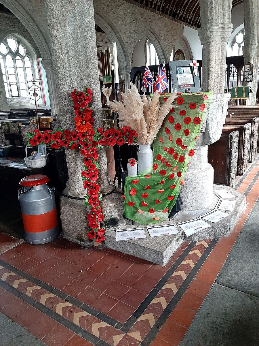 A Remembrance display of poppies, flags and commemorative material beside the granite pillars.